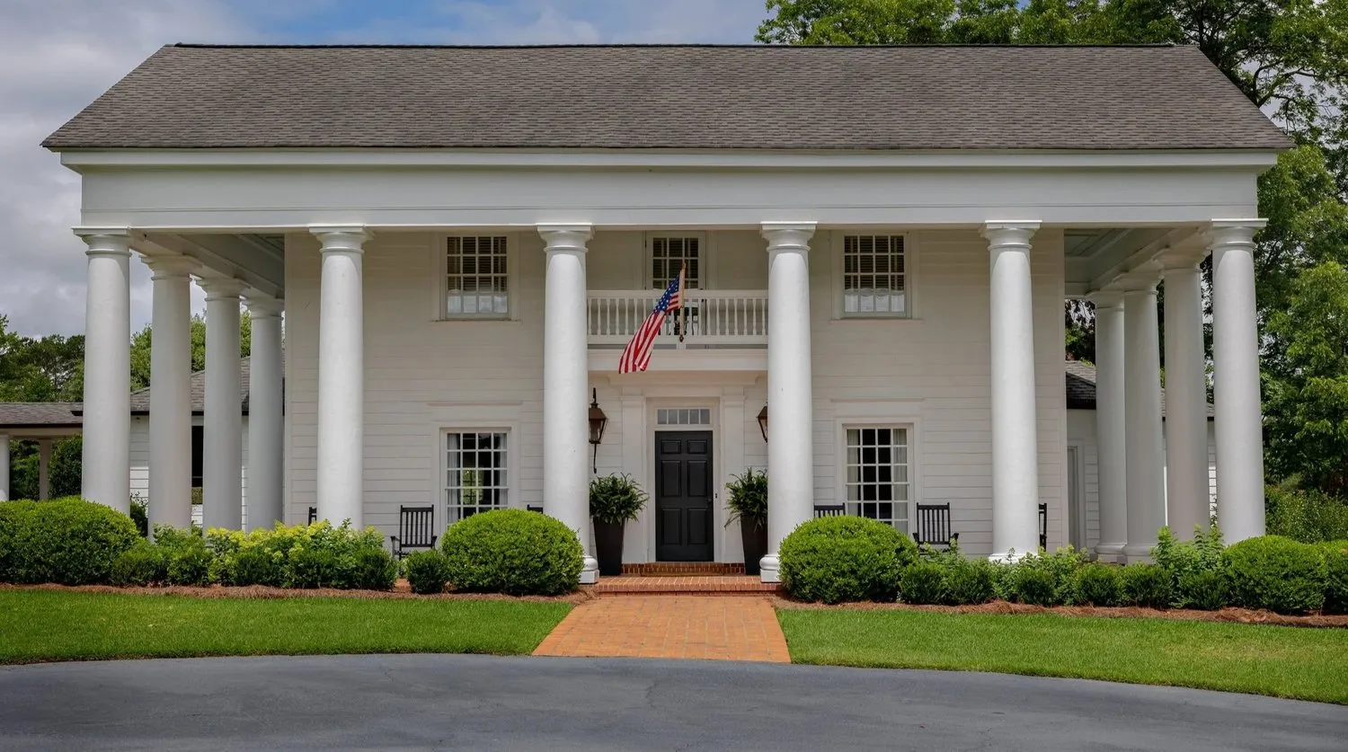 Grove Hill Farm, a white columned farmhouse behind a clipped lawn.