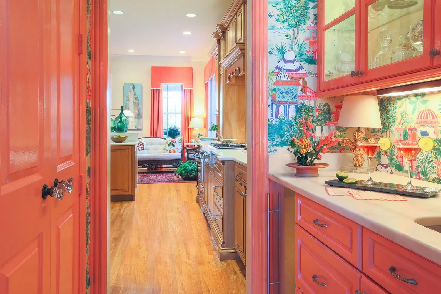 A coral lacquered butler's pantry opening to the kitchen, papered in a painted chinoiserie.